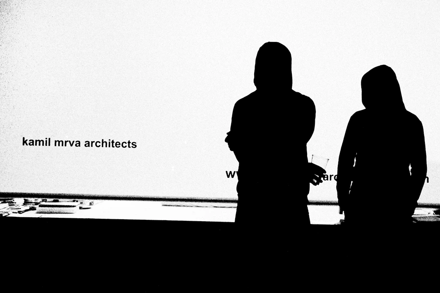 Black and white photo of two siluattes in front of Kamil Mrva Architects studio